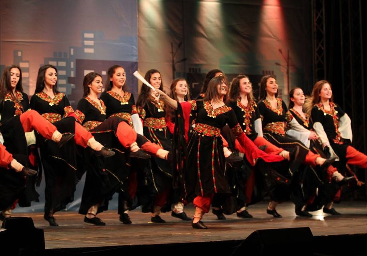 Girls in embroidered dresses dancing dabke in a line